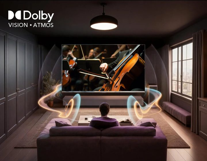 A viewer on a sofa in a dark cinema room, the screen showing a cellist, badged Dolby Vision and Atmos