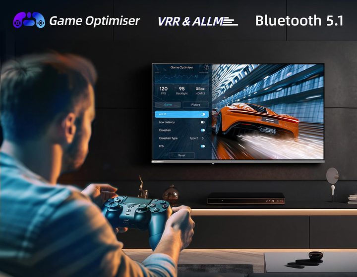A man with a game controller playing a racing game, badged Game Optimiser, VRR and ALLM, and Bluetooth 5.1